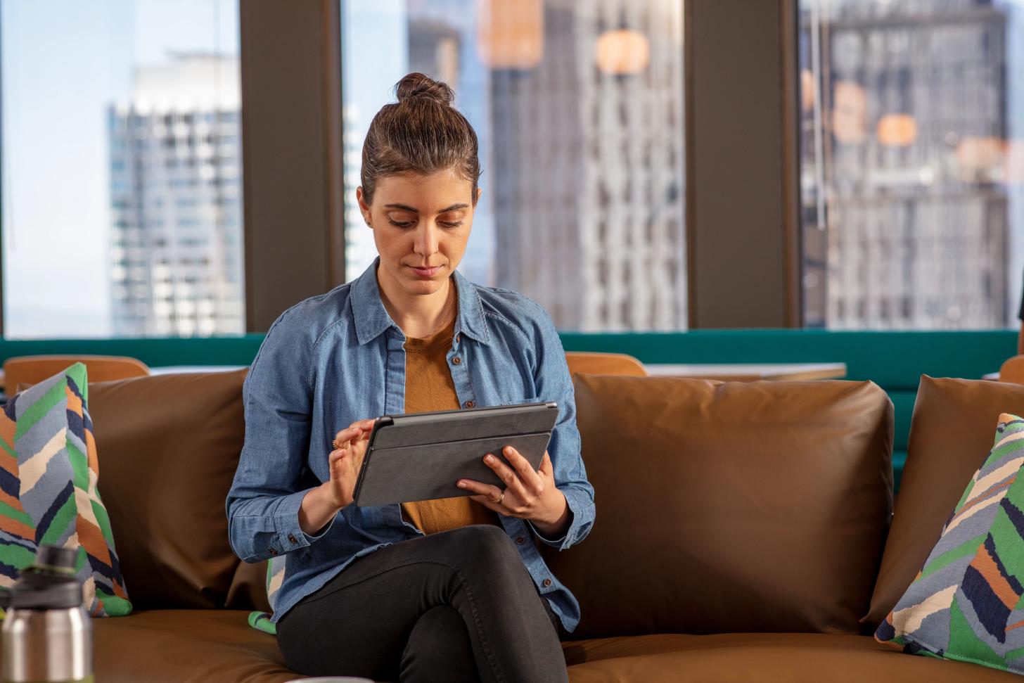 A developer sits on a couch looking at a tablet