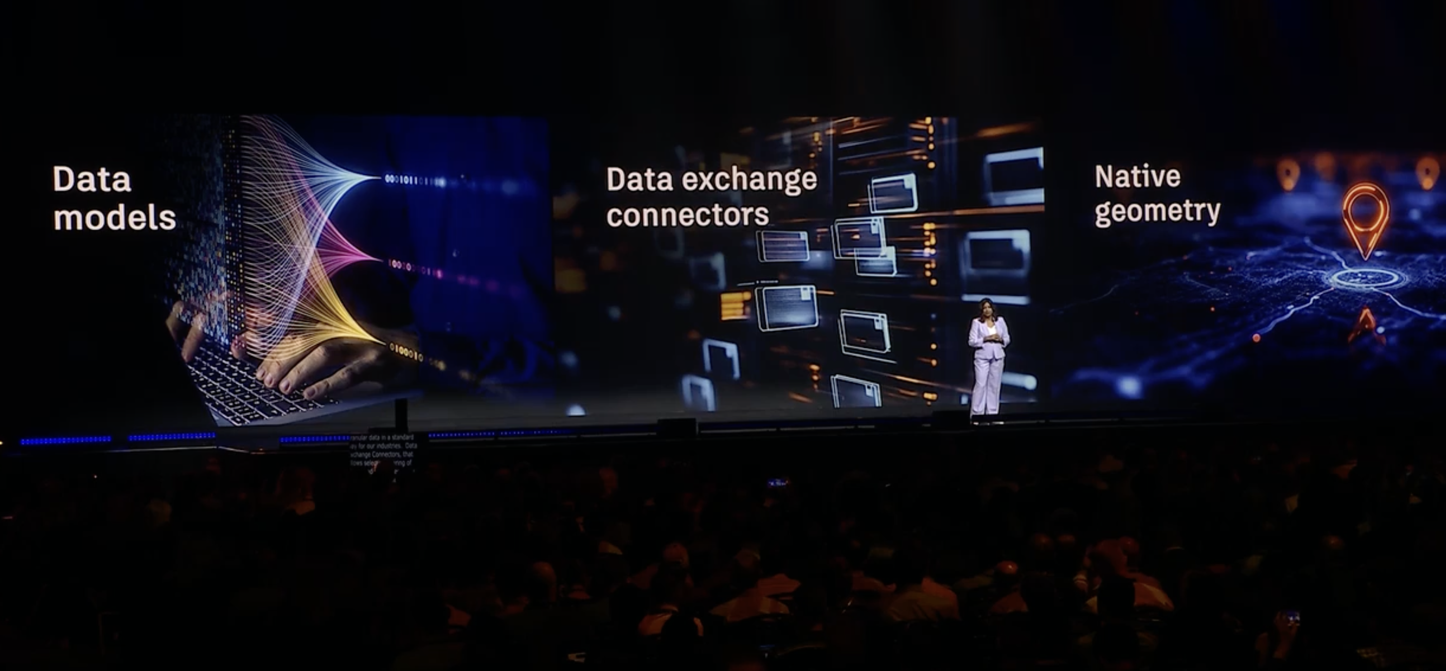 Photograph of CTO Raji Arasu speaking in front of a crowd at Autodesk University 2025. Background graphics include the phrases Data Models, Data Exchange Connectors, Data Geometry